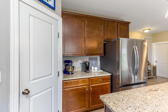 405 Tyler Station Dr, Johnstown, OH 43031 - kitchen featuring freestanding refrigerator, light stone counters, and brown cabinets
