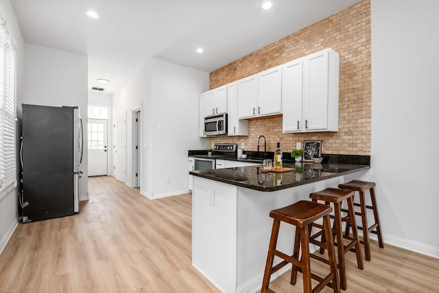 1116 Summit St Unit 1114, Columbus, OH 43201 - kitchen with stainless steel appliances, a sink, a peninsula, decorative backsplash, and white cabinets