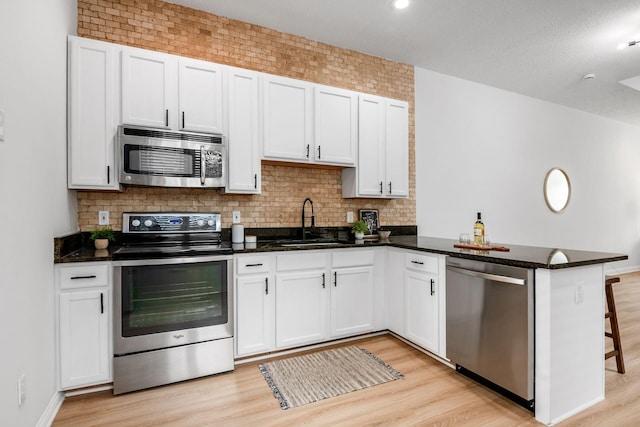 1116 Summit St Unit 1114, Columbus, OH 43201 - kitchen featuring stainless steel appliances, a sink, light wood finished floors, a peninsula, and white cabinets