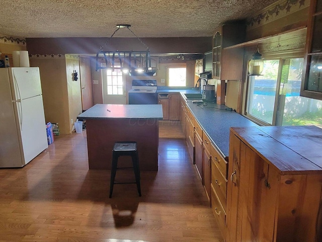 3813 N Old State Rd, Delaware, OH 43015 - kitchen with white appliances, wood finished floors, a center island, glass insert cabinets, and a textured ceiling