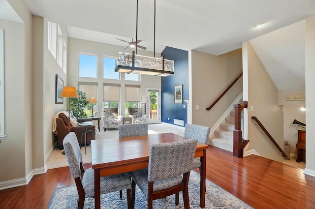6368 Casado Dr, Columbus, OH 43213 - dining area featuring wood finished floors, a ceiling fan, baseboards, a towering ceiling, and stairs