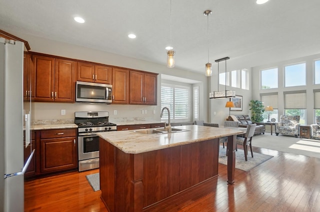 6368 Casado Dr, Columbus, OH 43213 - kitchen featuring appliances with stainless steel finishes, a sink, wood-type flooring, open floor plan, and light stone countertops