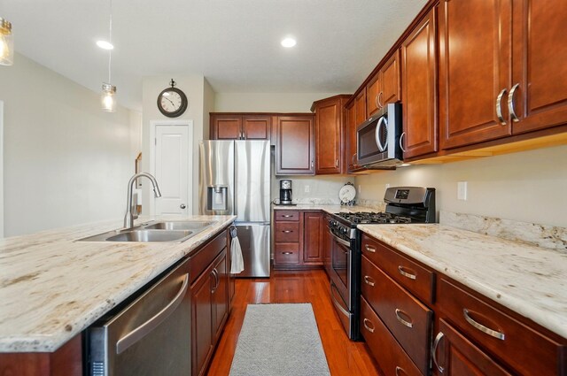 6368 Casado Dr, Columbus, OH 43213 - kitchen with appliances with stainless steel finishes, a sink, dark wood-style flooring, light stone countertops, and decorative light fixtures