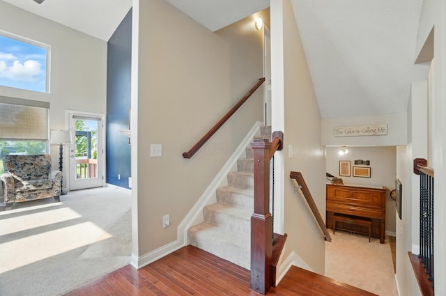 6368 Casado Dr, Columbus, OH 43213 - staircase with high vaulted ceiling, baseboards, wood finished floors, and carpet flooring