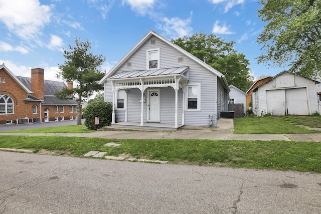 115 N Walnut St, Baltimore, OH 43105 - view of front of house featuring covered porch, a front lawn, a standing seam roof, an outbuilding, and metal roof