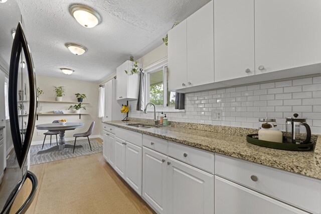 6576 Creon Dr, Reynoldsburg, OH 43068 - kitchen featuring a sink, freestanding refrigerator, a textured ceiling, white cabinetry, and tasteful backsplash