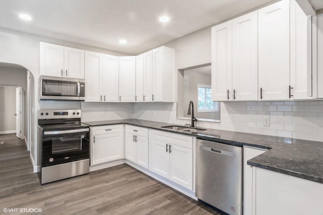 823 S Walnut St, Bucyrus, OH 44820 - kitchen featuring stainless steel appliances, a sink, white cabinetry, decorative backsplash, and wood finished floors
