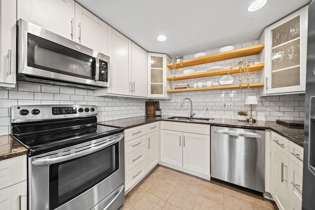 3600 Reed Rd Unit 13, Columbus, OH 43220 - kitchen with appliances with stainless steel finishes, a sink, tasteful backsplash, light tile patterned floors, and glass insert cabinets
