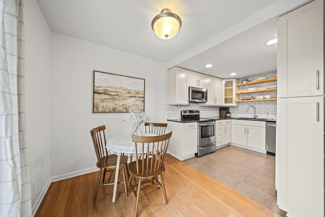 3600 Reed Rd Unit 13, Columbus, OH 43220 - kitchen featuring stainless steel appliances, a sink, dark countertops, decorative backsplash, and white cabinetry