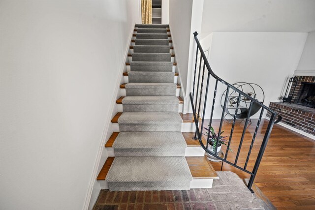 3600 Reed Rd Unit 13, Columbus, OH 43220 - staircase featuring wood finished floors, a brick fireplace, and baseboards