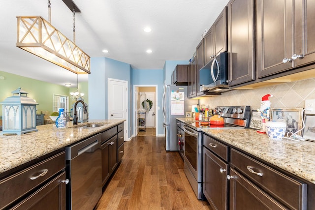 3736 Sanctuary, Hilliard, OH 43026 - kitchen with stainless steel appliances, dark brown cabinetry, a chandelier, tasteful backsplash, and dark wood-type flooring