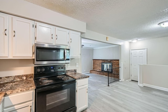 5359 Ivywood Ln, Columbus, OH 43229 - kitchen with stainless steel microwave, black range with electric cooktop, a textured ceiling, light wood-type flooring, and white cabinets