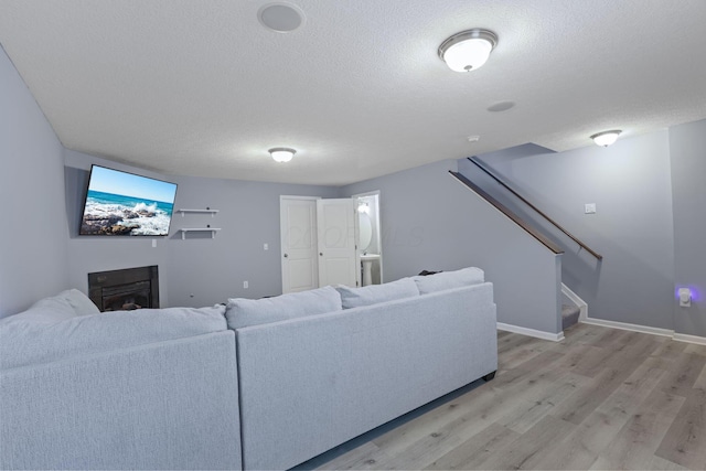 6310 Wagtail Rd Unit 6, Columbus, OH 43230 - living room featuring light wood-style flooring, stairway, a textured ceiling, a glass covered fireplace, and baseboards