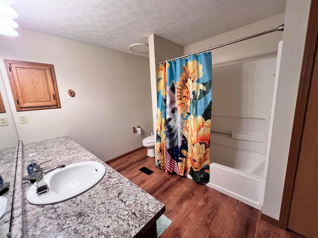 20600 Hellwig Rd, Utica, OH 43080 - bathroom with wood finished floors, vanity, toilet, a textured ceiling, and shower / bath combo