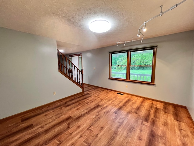20600 Hellwig Rd, Utica, OH 43080 - unfurnished room with wood finished floors, a textured ceiling, stairs, and baseboards