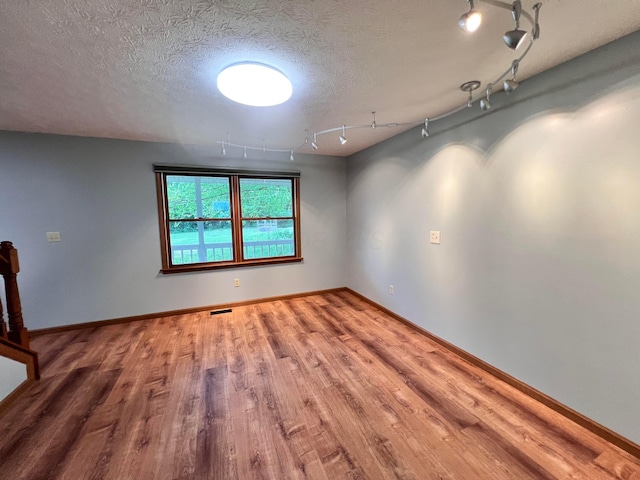 20600 Hellwig Rd, Utica, OH 43080 - empty room with wood finished floors, rail lighting, baseboards, and a textured ceiling