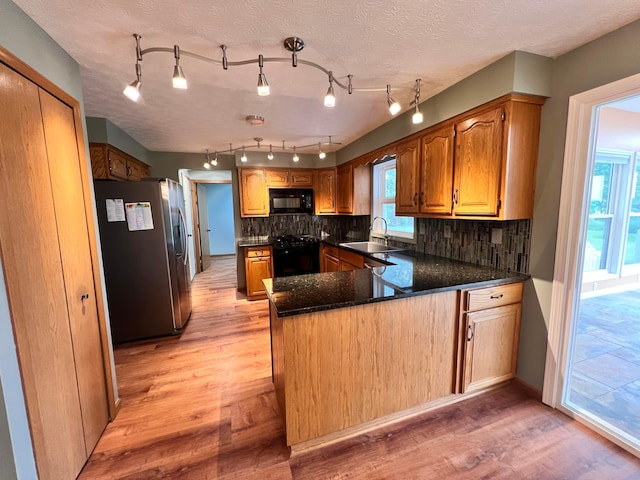 20600 Hellwig Rd, Utica, OH 43080 - kitchen with black appliances, a peninsula, a sink, light wood-style flooring, and backsplash