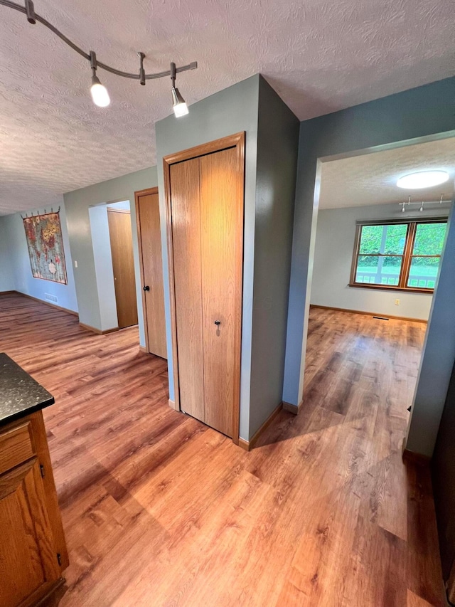 20600 Hellwig Rd, Utica, OH 43080 - hallway featuring a textured ceiling, wood finished floors, track lighting, and baseboards