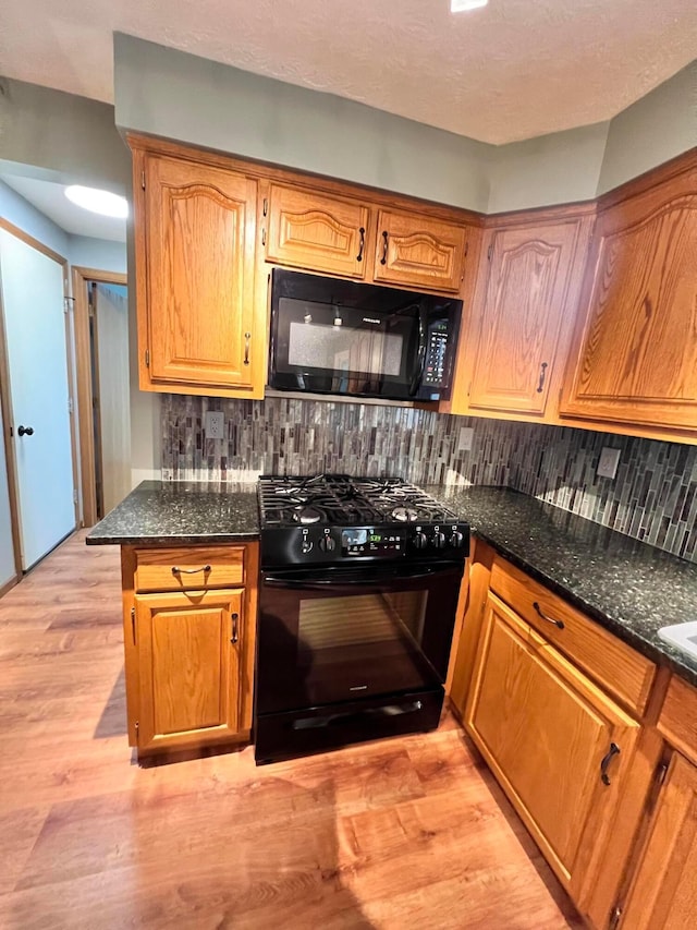 20600 Hellwig Rd, Utica, OH 43080 - kitchen featuring black appliances, tasteful backsplash, light wood finished floors, dark stone counters, and brown cabinets