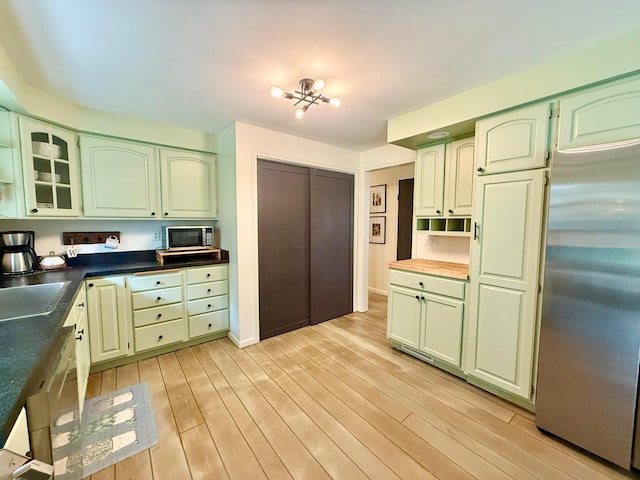 1855 Itawamba Trl, London, OH 43140 - kitchen featuring stainless steel appliances, green cabinetry, light wood-style flooring, glass insert cabinets, and a sink