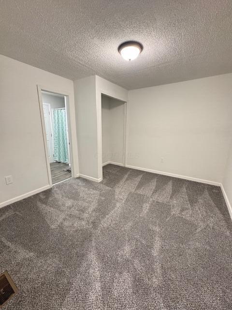 1729 E 17th Ave, Columbus, OH 43219 - unfurnished bedroom with dark colored carpet, a textured ceiling, baseboards, and a closet