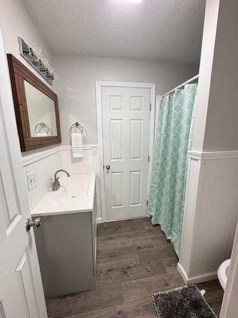 1729 E 17th Ave, Columbus, OH 43219 - bathroom featuring a textured ceiling, wainscoting, vanity, wood finished floors, and toilet