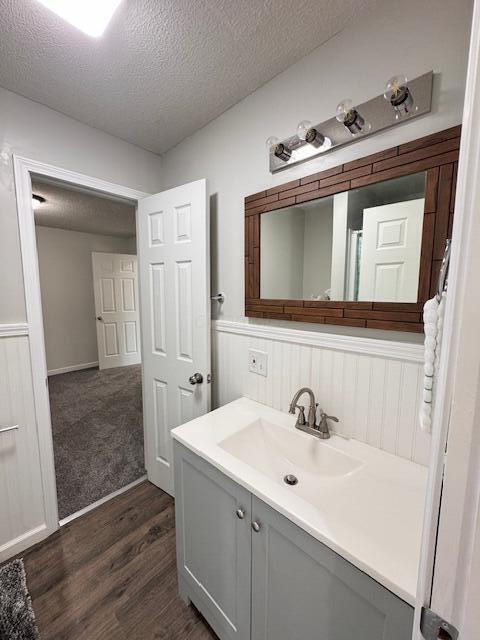 1729 E 17th Ave, Columbus, OH 43219 - bathroom with a textured ceiling, wood finished floors, vanity, and wainscoting