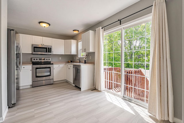 8281 Deering Oaks Dr, Blacklick, OH 43004 - kitchen featuring appliances with stainless steel finishes, white cabinetry, light countertops, and a sink