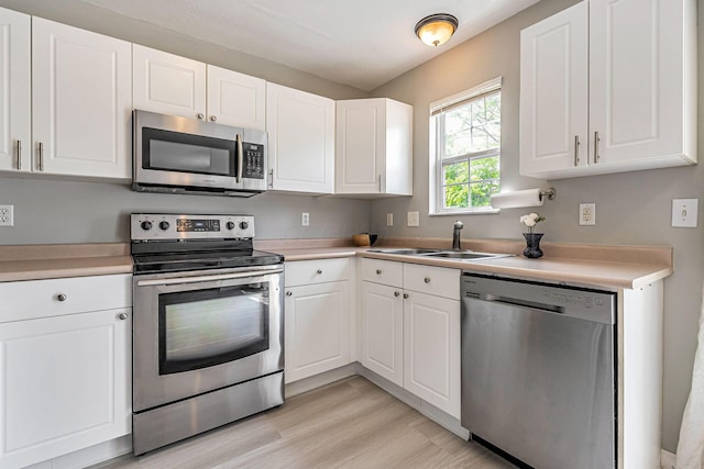 8281 Deering Oaks Dr, Blacklick, OH 43004 - kitchen with stainless steel appliances, a sink, white cabinetry, light countertops, and light wood finished floors