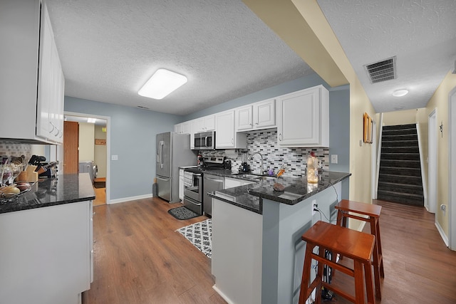 4654 Collingville Way, Columbus, OH 43230 - kitchen featuring appliances with stainless steel finishes, a sink, a textured ceiling, a breakfast bar area, and white cabinets