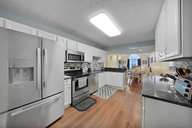 4654 Collingville Way, Columbus, OH 43230 - kitchen with stainless steel appliances, a peninsula, light wood-style floors, white cabinetry, and backsplash