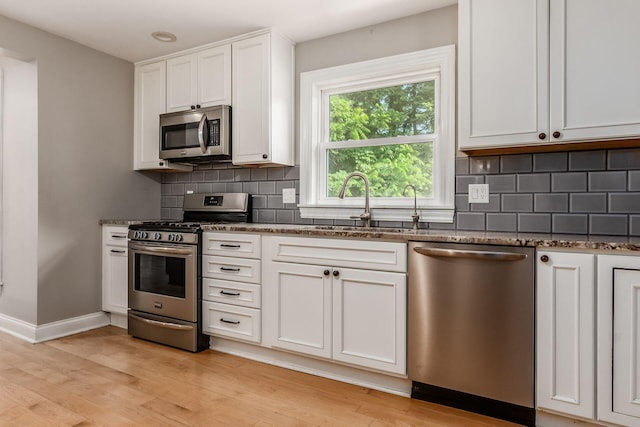 6900 Waterloo Rd NW, Canal Winchester, OH 43110 - kitchen with appliances with stainless steel finishes, dark stone countertops, light wood-type flooring, and white cabinets