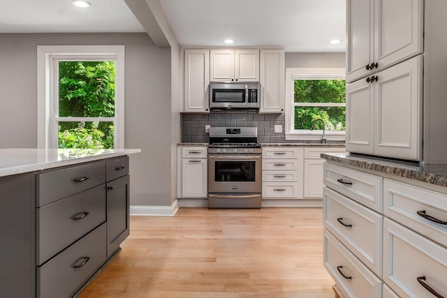 6900 Waterloo Rd NW, Canal Winchester, OH 43110 - kitchen with appliances with stainless steel finishes, healthy amount of natural light, backsplash, light wood-type flooring, and recessed lighting
