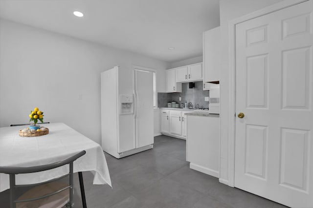 2217 Grasmere Ave, Columbus, OH 43211 - kitchen featuring white refrigerator with ice dispenser, white cabinets, light countertops, tasteful backsplash, and dark tile patterned flooring