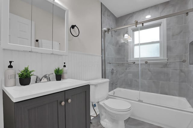 2217 Grasmere Ave, Columbus, OH 43211 - bathroom with vanity, toilet, bath / shower combo with glass door, a wainscoted wall, and tile patterned flooring