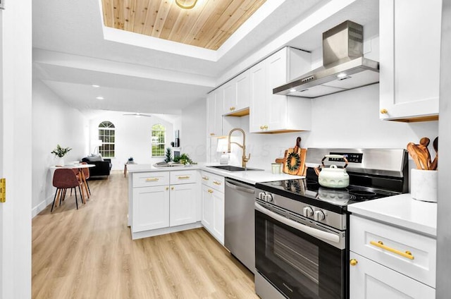 560 Dandy Brush Ln E, Columbus, OH 43230 - kitchen featuring stainless steel appliances, wall chimney range hood, a sink, white cabinetry, and a raised ceiling