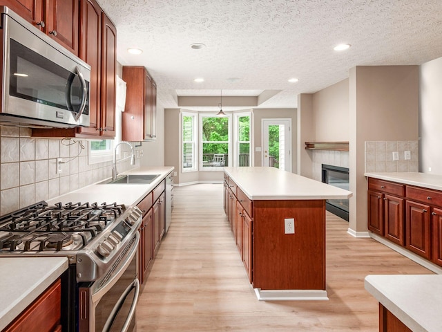 7034 Kellogg Dr, Powell, OH 43065 - kitchen with a sink, stainless steel appliances, a textured ceiling, light wood-style floors, and a center island