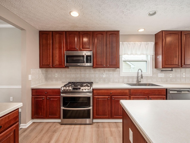 7034 Kellogg Dr, Powell, OH 43065 - kitchen with appliances with stainless steel finishes, a sink, light wood-style floors, tasteful backsplash, and light countertops
