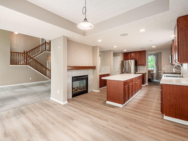 7034 Kellogg Dr, Powell, OH 43065 - kitchen with stainless steel appliances, open floor plan, a textured ceiling, a kitchen island, and light wood-style flooring