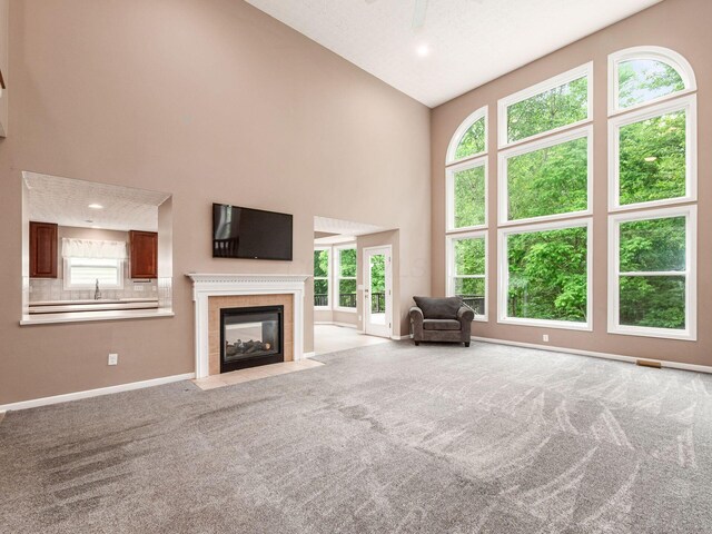 7034 Kellogg Dr, Powell, OH 43065 - carpeted living area featuring high vaulted ceiling, baseboards, a sink, a tiled fireplace, and plenty of natural light