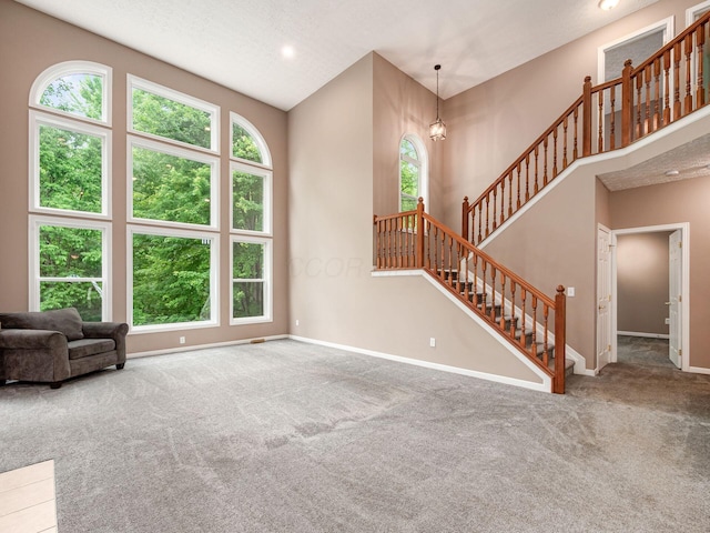 7034 Kellogg Dr, Powell, OH 43065 - unfurnished living room featuring carpet flooring, baseboards, stairs, recessed lighting, and a high ceiling