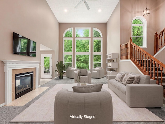 7034 Kellogg Dr, Powell, OH 43065 - living room featuring a high ceiling, a ceiling fan, plenty of natural light, stairway, and a tile fireplace
