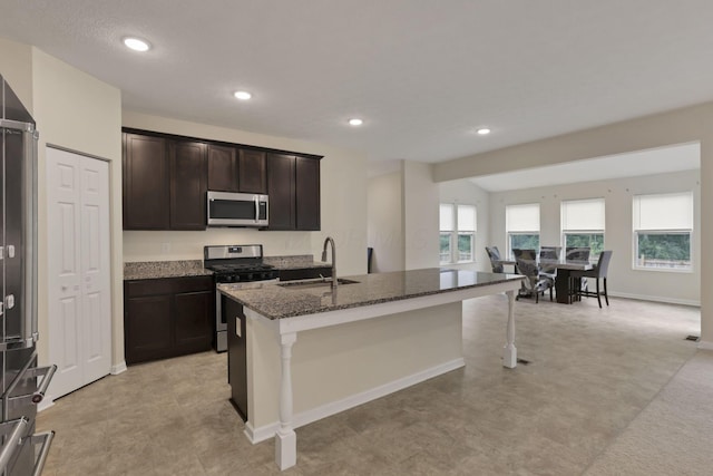 1137 Legacy Ln, Pataskala, OH 43062 - kitchen with appliances with stainless steel finishes, a sink, dark stone counters, a kitchen island with sink, and a kitchen breakfast bar