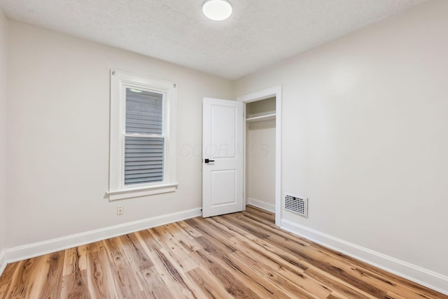 1113-1115 S Ohio Ave, Columbus, OH 43206 - unfurnished bedroom featuring baseboards, light wood finished floors, and a textured ceiling