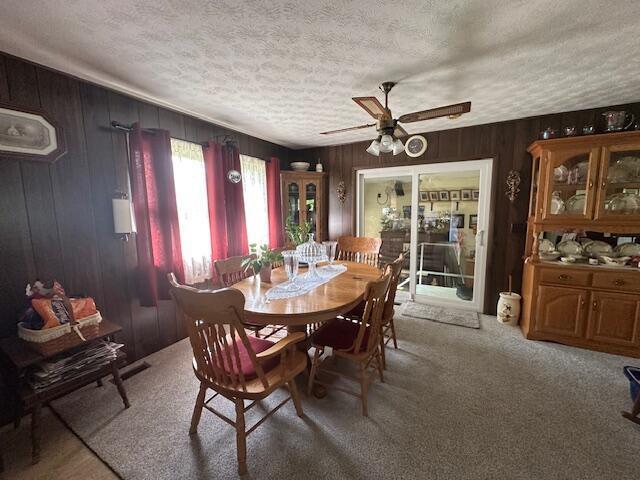 14572 Hock Hocking Rd, Logan, OH 43138 - dining area featuring ceiling fan, a textured ceiling, carpet, and wooden walls