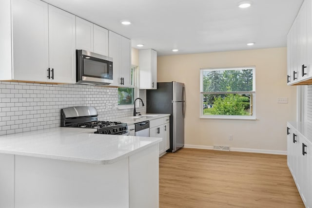 1345 E Deshler Ave, Columbus, OH 43206 - kitchen featuring appliances with stainless steel finishes, a sink, light wood finished floors, backsplash, and white cabinets
