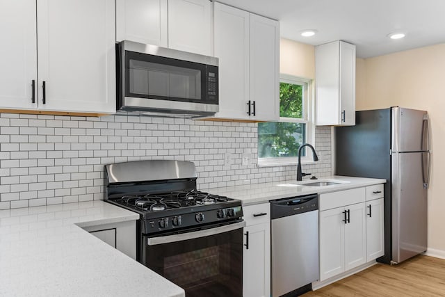 1345 E Deshler Ave, Columbus, OH 43206 - kitchen with stainless steel appliances, a sink, light stone counters, white cabinetry, and light wood finished floors