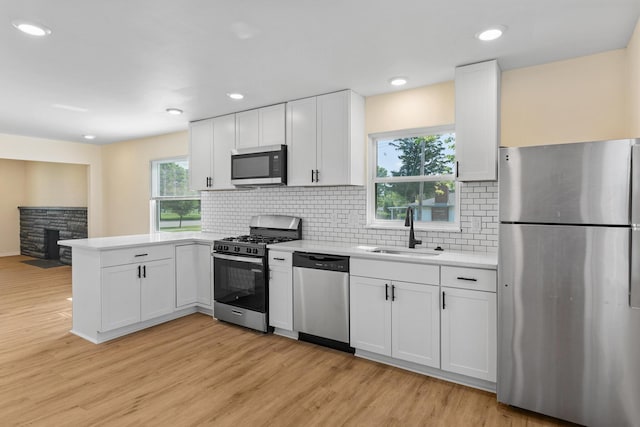 1345 E Deshler Ave, Columbus, OH 43206 - kitchen with appliances with stainless steel finishes, a sink, a peninsula, light countertops, and light wood-style floors