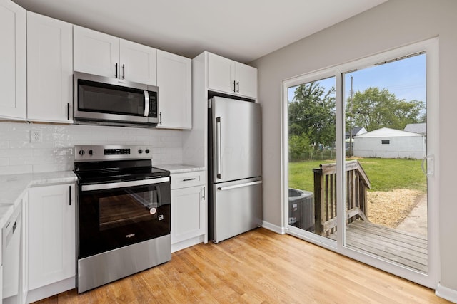 1001 S Harris Ave, Columbus, OH 43204 - kitchen featuring appliances with stainless steel finishes, tasteful backsplash, white cabinetry, light wood-style floors, and light stone counters