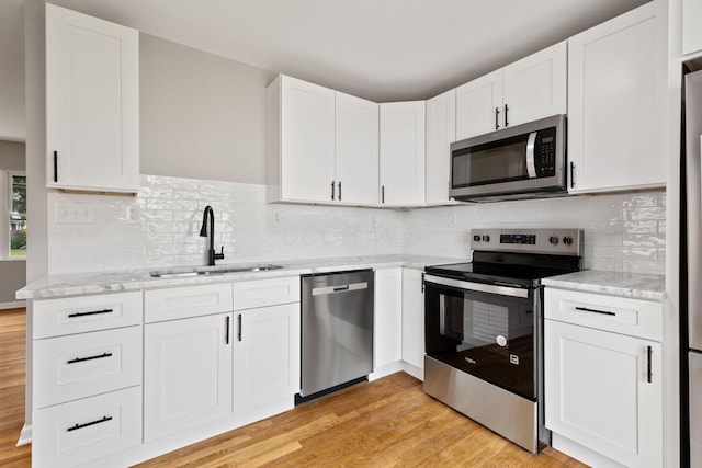 1001 S Harris Ave, Columbus, OH 43204 - kitchen with stainless steel appliances, a sink, light stone counters, and light wood-type flooring